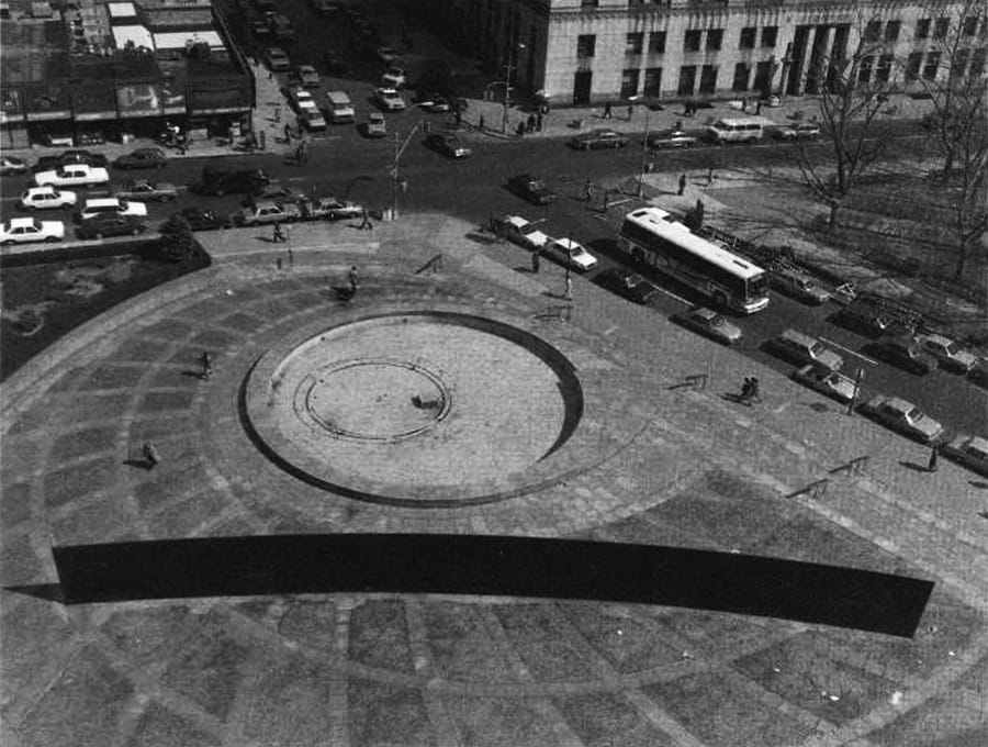 Black-and-white aerial photograph of Richard Serra's Tilted Arc sculpture in the middle of a NYC plaza.