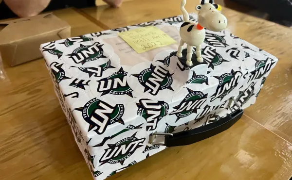 A homemade time capsule, built from a cash-box and sealed using dozens of vinyl stickers that read "UNT".