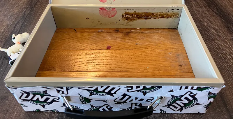 An open banking cash box, whose bottom surface is covered with oak strips, appearing like a hardwood floor